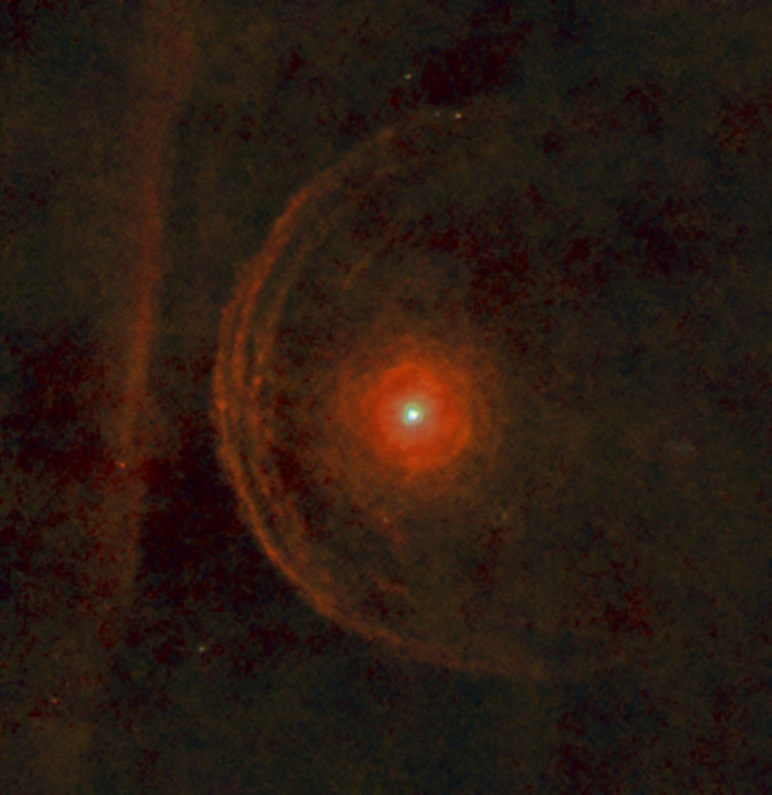 An RGB image of Betelgeuse and its environment constructed from PACS images at 70, 100 and 160 microns. North is to the top left and east to the bottom left in this view. A series of arcs can be see to the left (northeast) of the star; these are shells of material shed by the star in its supergiant phase. An intriguing feature of this image is the vertical bar to the left, which it is hypothesised may be the edge of an interstellar cloud that is being illuminated by the star; if so, the outer shell will collide with it in approximately 5000 years.