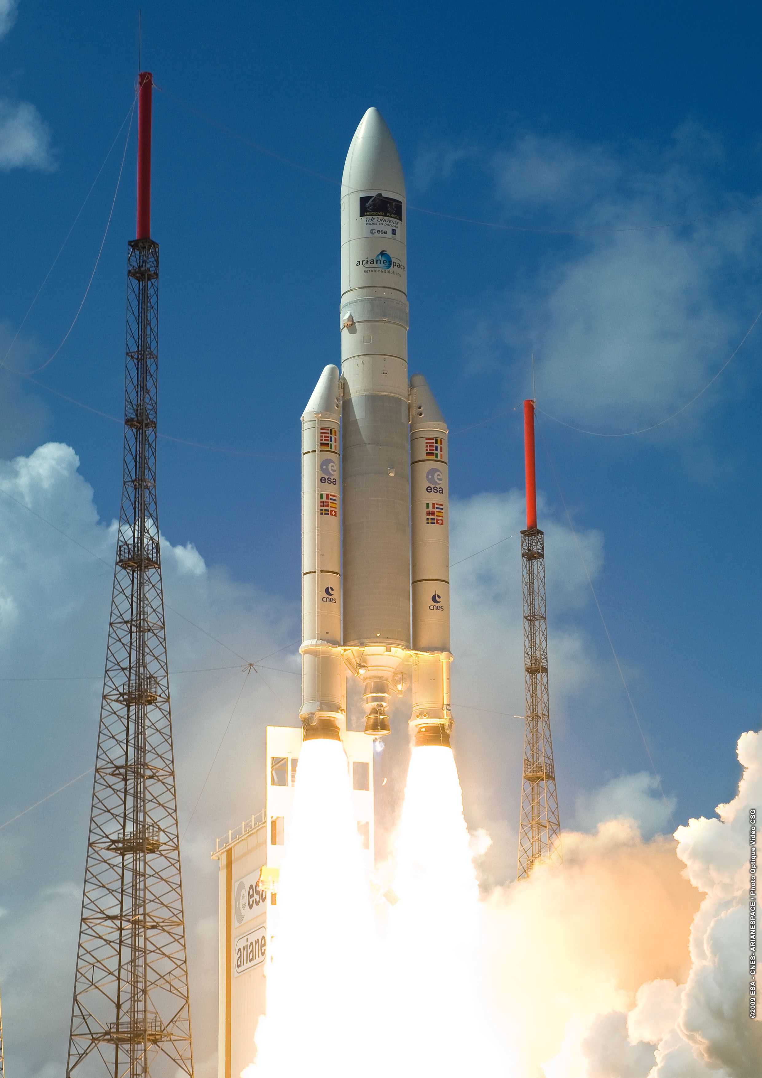Launch of the Herschel-Planck mission on an Ariane 5-ECA at 13:12:02UT on 14 May 2009. The Herschel-Planck mission logo is clearly visible at the top of the fairing. The fine weather and clear blue sky contrasts sharply with the conditions for roll-out (), or those prevalent only a few hours before launch as the VIPs were taken to the launch viewing area in heavy rain during an intense storm.